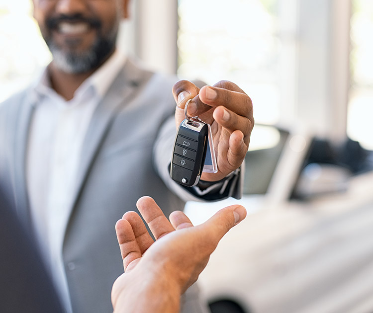 A car salesperson handing new car keys to customer.
