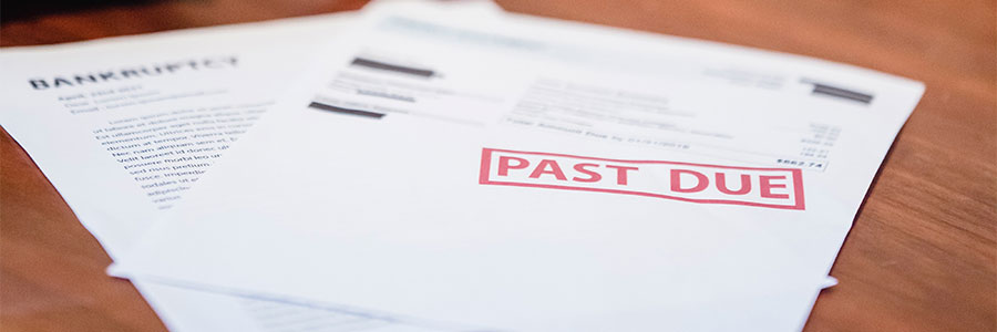 Image of paper statements on a table with one stamped "Past Due."