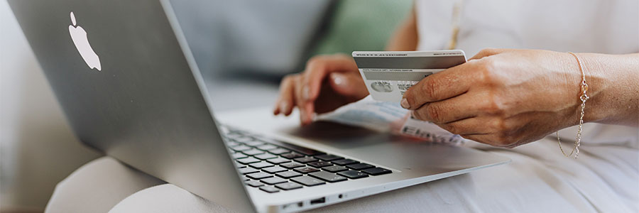 Image of a person holding a credit card while typing on a laptop sitting on a couch.