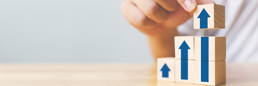 Hand stacking blocks in a step shape representing growth.